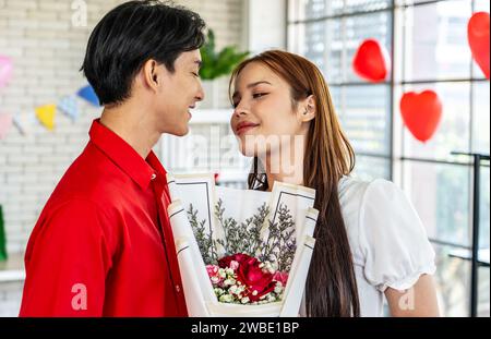 Ein junger Mann, der einer schönen Frau einen Blumenstrauß überreicht Stockfoto