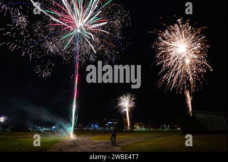 Mein Sohn und ich stehen still und sehen uns ein Feuerwerk aus der Ferne an und feiern das neue Jahr 2024. Die Explosionen waren wirklich spektakulär Stockfoto