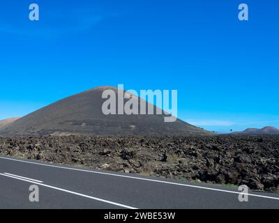 Panoramablick auf leere Asphaltstraße LZ-67 in vulkanischer Landschaft des Timanfaya Nationalparks, Lanzarote, Kanarische Inseln, Spanien, Europa Stockfoto