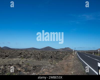 Panoramablick auf leere Asphaltstraße LZ-67 in vulkanischer Landschaft des Timanfaya Nationalparks, Lanzarote, Kanarische Inseln, Spanien, Europa Stockfoto