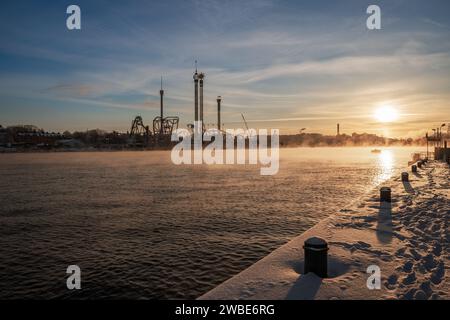 Rauchende See, Meeresrauch, in Stockholm aufgrund der arktischen Kälte und der Vergnügungspark Grona lund im Hintergrund, Sonne und Schnee. Stockfoto