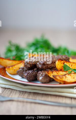 Lula Kebabs auf einem weißen Teller mit rotem Rand mit gebackenen Kartoffeln und Grünzeug. Lamb Lula Kebab, Rindfleisch lula Kebab, Huhn lula Kebab Nahaufnahme. Vertikal Stockfoto