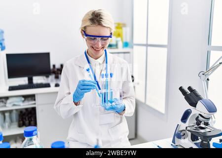 Junge blonde Wissenschaftlerin, die Reagenzgläser im Labor analysiert Stockfoto