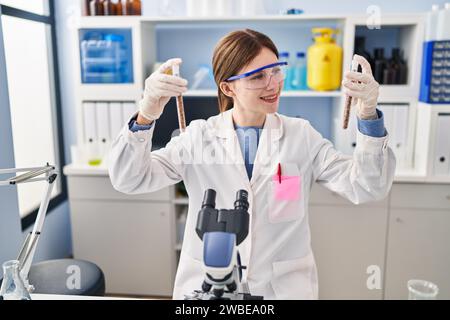 Junge blonde Wissenschaftlerin, die Reagenzgläser im Labor analysiert Stockfoto