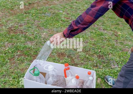 Der Mensch sammelt leere Plastikflaschen im Feld, um sie zu recyceln, Konzept der Ökologie und Respekt für die Umwelt. Stockfoto