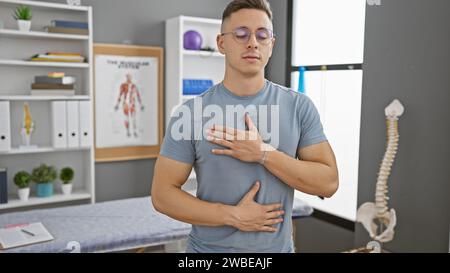 Ein junger hispanischer Mann mit geschlossenen Augen, der in einer Klinik tief durchatmet und ein Gefühl von Gesundheit und Wohlbefinden schafft. Stockfoto