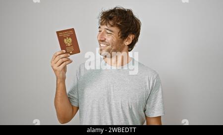 Ein glücklicher junger Mann, der vor Freude strahlt, hält stolz seinen polnischen Pass vor einem isolierten weißen Hintergrund fest Stockfoto