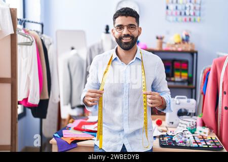 Ein junger arabischer Schneider, der selbstbewusst im Schneiderladen steht Stockfoto