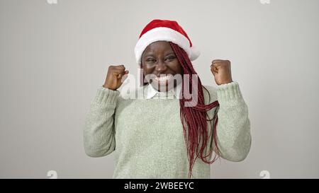 Afrikanische Frau mit geflochtenen Haaren, die weihnachtsmütze über weißem Hintergrund feiert Stockfoto