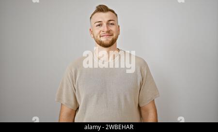 Lächelnder junger bärtiger Mann in lässiger Kleidung, der vor einem isolierten weißen Hintergrund steht Stockfoto