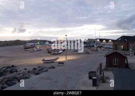 Eine lebendige dörfliche Uferszene in der Abenddämmerung mit mehreren Booten, die entlang der Küste angedockt sind. Stockfoto