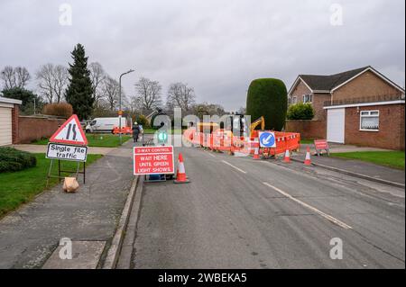 Fußweg geschlossen und Ampel steuert den Straßenverkehr auf einer Stadtstraße mit Warnschildern und Barrieren rund um das Gelände. Stockfoto