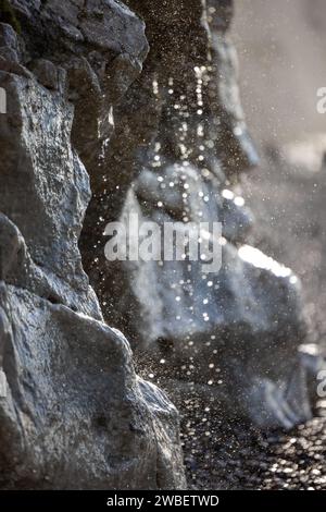 Dieses Bild konzentriert sich auf den Moment, in dem das Wasser am Rand einer Klippe herabstürzt und durch das Sonnenlicht in einen Schauer aus funkelnden Juwelen verwandelt wird. Die zerklüfteten Strukturen der Klippe werden durch die Sonnenstrahlen verstärkt, die den Kontrast zwischen der Permanenz des Steins und der Vergänglichkeit des Wassers hervorheben. Die Tropfen werden in einem Freeze-Frame der Bewegung gefangen, ein Spektakel der Kunstfertigkeit der Natur in Aktion. Elementarer Tanz: Sonnendurchfluteter Wasserfall an der Cliffside. Hochwertige Fotos Stockfoto