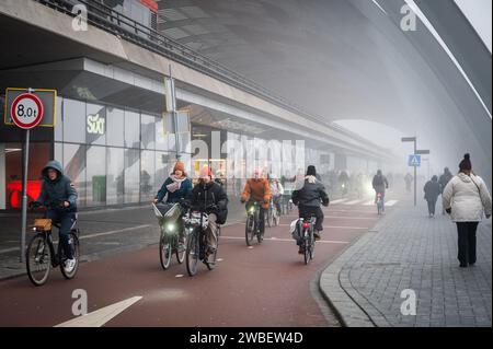 Pendler fahren an einem kalten, nebeligen Morgen am Bahnhof Amsterdam Centraal auf Radwegen zur Arbeit Stockfoto