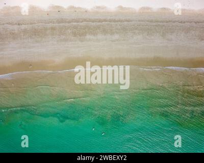 Blick von oben auf Surfer, die auf Wellen an einem tropischen Strand warten Stockfoto