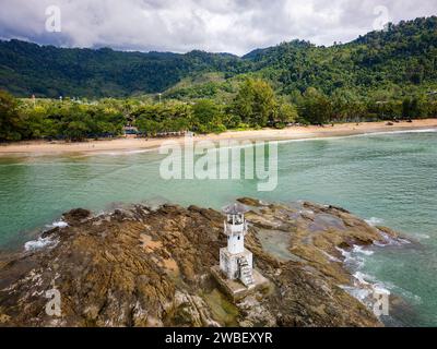 Blick aus der Vogelperspektive auf einen kleinen Leuchtturm auf einem Felsen vor der Küste von einem tropischen Strand Stockfoto