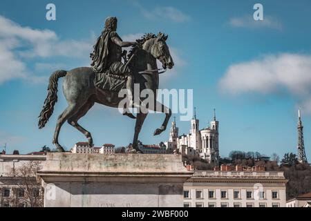 Lyon, Frankreich - 30. Januar 2022: Reiterskulptur des Königs Ludwig XIV. Und die Basilika Fourviere auf dem Hintergrund, Bellecour-Platz in Lyon, Fr. Stockfoto