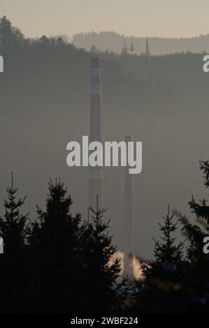 Hoher alter Schornstein im Industriegebiet und nebeliger Sonnenuntergang im Hintergrund. Roznov Pod Radhostem, Tschechische republik. Stockfoto