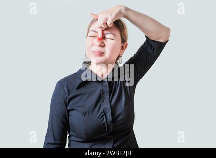 Junge Frau mit Schmerzen, die die Nase berühren. Menschen mit Nasenbrückenschmerzen, Mädchen mit Nasenbrückenschmerzen. Sinusschmerz-Konzept Stockfoto