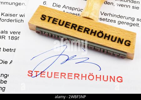 Ein Holzstempel liegt auf einem Dokument. Deutsche Inschrift: Steuererhoehung Stockfoto