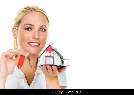 Eine Frau beschützt Ihr Haus und Ihr Zuhause. Gute Versicherung und ernsthafte Finanzierung beruhigen, blond, 30 Jahre, Modellhaus, Hausschlüssel Stockfoto