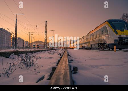 Trainiere auf schneebedeckten Gleisen bei Sonnenuntergang mit Fokus auf den Vordergrund, Pforzheim, Deutschland Stockfoto