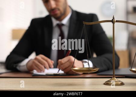 Anwalt arbeitet am Tisch im Büro, konzentriert sich auf die Maßstäbe der Gerechtigkeit Stockfoto