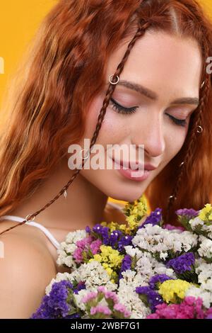 Schöne junge Hippie-Frau mit Blumenstrauß auf orangem Hintergrund, Nahaufnahme Stockfoto