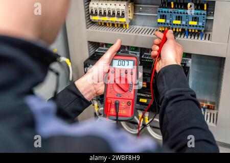 Arbeiter, der eine elektrische Systemtafel in einem Werk misst und repariert Stockfoto