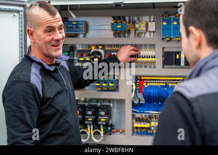 Zwei männliche Arbeiter eines Industrietechnikers, der elektrische mechanische Systeme in einer Fabrik installiert und gewartet hat Stockfoto