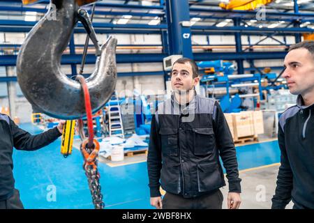 Drei männliche Ingenieure einer Logistikfabrik mit Industriekran Stockfoto