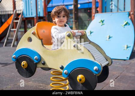 Ein süßes kleines Mädchen, das auf einem Spielplatz spielt, in Form eines Autos Stockfoto