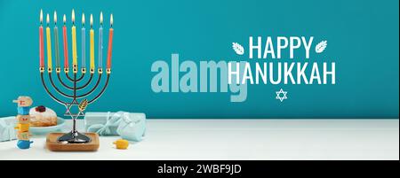 Happy Hanukkah. Menora, Donut, Dreidels und Geschenke auf weißem Tisch, Banner-Design Stockfoto