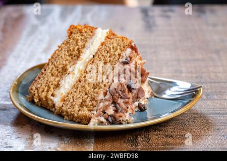 Eine Portion oder Portion Cappuccino-Kaffeekuchen, die auf einem Kaffeetisch serviert werden. Der Kuchen ist zweistufig und hat eine Buttercremefüllung und eine Platte Stockfoto