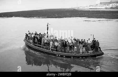 1960, historisch, eine Gruppe von Urlaubern, die eine Fahrt mit dem Margate Rettungsboot machen, Margate, Kent, England, Großbritannien. Das Bootshaus und die Rutsche für das Rettungsboot RNLI wurden 1898 an den Pier Margate angeschlossen und bis 1978 betrieben, als ein schwerer Sturm den Großteil der bereits zwei Jahre zuvor aus Sicherheitsgründen stillgelegten Anlegestelle zerstörte. Stockfoto