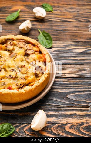 Pilzkuchen mit Spinatblättern und Champignons auf einem Holztisch Stockfoto