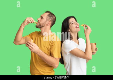 Schönes junges Paar, das Pommes frites auf grünem Hintergrund isst Stockfoto