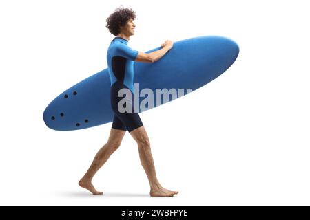 Profilaufnahme eines Mannes in einem Neoprenanzug, der ein Surfbrett auf weißem Hintergrund trägt Stockfoto