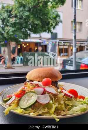 Ein frisch zubereitetes Sandwich auf einem weißen Teller vor einem Fenster, mit Sonnenlicht durchströmt Stockfoto