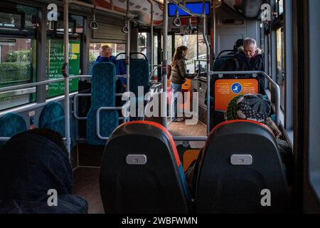 Blick aus dem Inneren eines Busses auf einer Stadtstrecke - Innenraum des Busses mit Passagieren und jemand, der ein Ticket kauft. UK. Konzepttransport. Nachhaltiges Reisen. Stockfoto