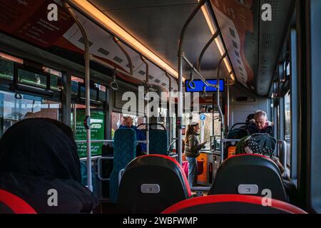 Blick aus dem Inneren eines Busses auf einer Stadtstrecke - Innenraum des Busses mit Passagieren und jemand, der ein Ticket kauft. UK. Konzepttransport. Nachhaltiges Reisen. Stockfoto