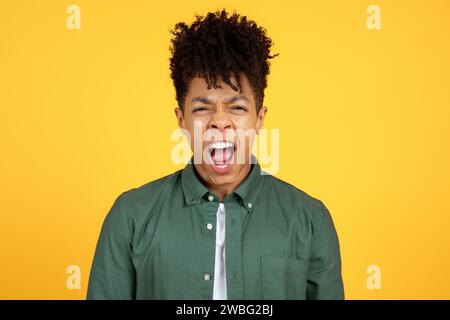 Schreiender junger afroamerikanischer Mann, isoliert auf gelbem Hintergrund Stockfoto