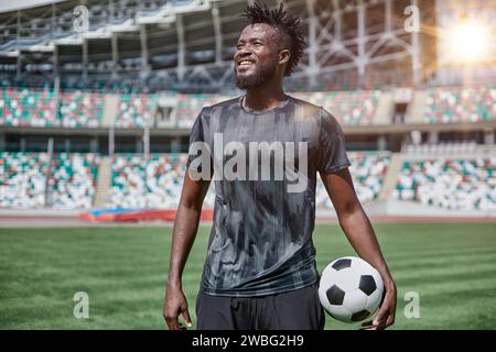 Ein junger Mann steht in einem Stadion mit einem Fußball in der Hand Stockfoto