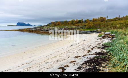 Sitzbereich am Strand von Sommarøya, Grillbereich am Ufer des Nordatlantiks, in Troms, Norwegen. Parkbank aus Holz mit Tisch, Esstisch, Kamin Stockfoto