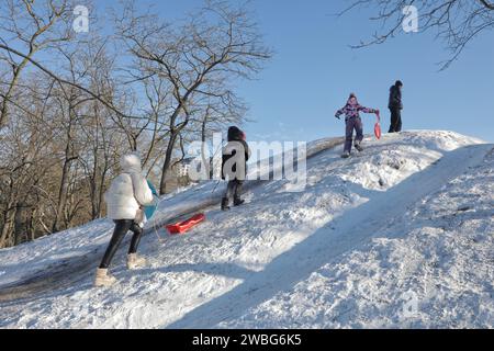 Nicht exklusiv: ODESA, UKRAINE - 10. JANUAR 2024 - Kinder fahren bergauf, während sie im Premohy (Victory) Park, Odesa, Süd-Ukraine, Schlitteln. Stockfoto