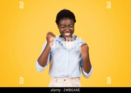 Glückliche junge afroamerikanische Studentin, die Triumph und Freude ausstrahlt Stockfoto