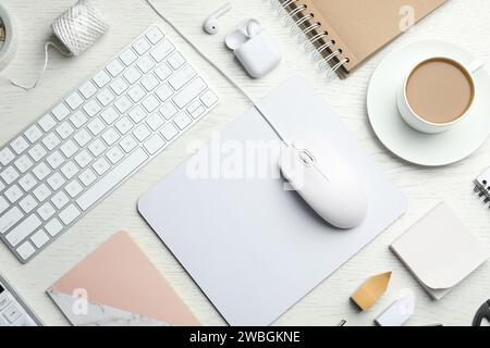 Flache Verlegung mit kabelgebundener Computermaus, Tastatur und Schreibwaren auf weißem Holztisch Stockfoto