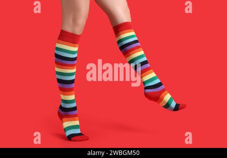 Frau in stilvollen Regenbogensocken auf rotem Hintergrund, Großaufnahme Stockfoto