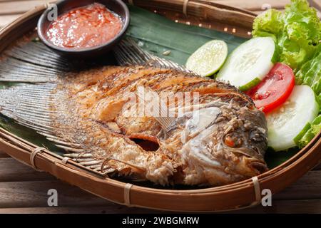 Frittierter Gourami-Fisch mit scharfer Sauce in einem Bambusbehälter, dekoriert mit Gemüse Stockfoto