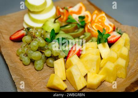 Eine lebhafte Auswahl an frischen Früchten, darunter Trauben, Erdbeeren, Ananas und Kiwi, schön arrangiert für einen Snack oder eine Party. Stockfoto